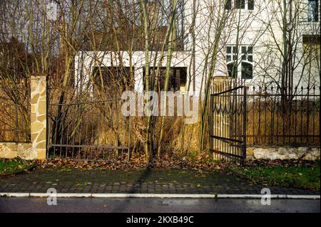 une maison abandonnée portes d'entrée brisées et clôture métallique à tête de fer, image légèrement tonifiée pour plus d'expression Banque D'Images