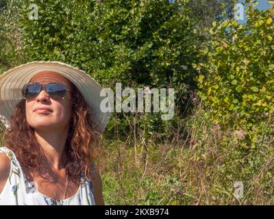 portrait d'une femme portant un chapeau à large bord et posant à l'extérieur Banque D'Images
