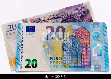 Une note de banque de vingt euros et une note de vingt livres sterling de Grande-Bretagne isolées sur fond blanc. Banque D'Images