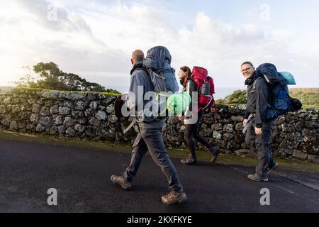 Groupe d'amis randonnée avec de grands sacs à dos sur une route dans les Açores Banque D'Images