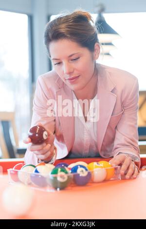 femme mettant en place des boules de billard dans un cadre triangulaire transparent Banque D'Images