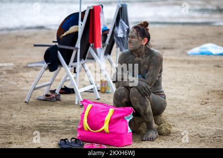 Les gens ont couvert de boue à la plage dans un petit endroit de la Meline, île Krk, Croatie, 14 août,2020. Du début du printemps à la fin de l'automne, la plage du village de Melina est l'une des plus visitées de l'île grâce à la boue curative qui couvre la plage. Les bénéfices de la boue ont été reconnus par beaucoup, en particulier les patients atteints de polyarthrite rhumatoïde qui, après s'être enveloppés de boue, se sentent un grand soulagement.photo: Nel Pavletic/PIXSELL Banque D'Images