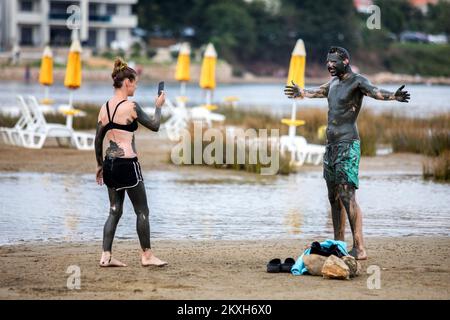 Une femme photographie un homme couvert de boue à la plage dans un petit endroit de Meline, île Krk, Croatie, 14 août,2020. Du début du printemps à la fin de l'automne, la plage du village de Melina est l'une des plus visitées de l'île grâce à la boue curative qui couvre la plage. Les bénéfices de la boue ont été reconnus par beaucoup, en particulier les patients atteints de polyarthrite rhumatoïde qui, après s'être enveloppés de boue, se sentent un grand soulagement.photo: Nel Pavletic/PIXSELL Banque D'Images