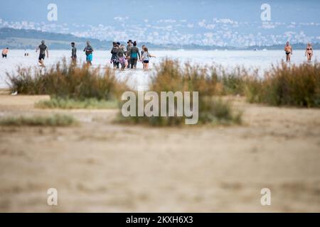 Les gens ont couvert de boue à la plage dans un petit endroit de la Meline, île Krk, Croatie, 14 août,2020. Du début du printemps à la fin de l'automne, la plage du village de Melina est l'une des plus visitées de l'île grâce à la boue curative qui couvre la plage. Les bénéfices de la boue ont été reconnus par beaucoup, en particulier les patients atteints de polyarthrite rhumatoïde qui, après s'être enveloppés de boue, se sentent un grand soulagement.photo: Nel Pavletic/PIXSELL Banque D'Images