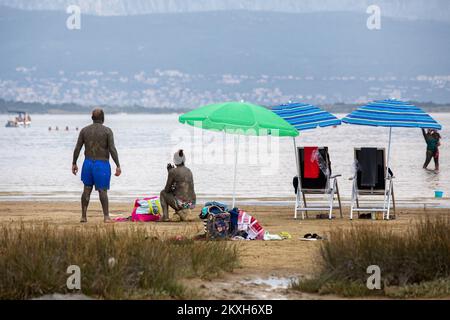 Les gens ont couvert de boue à la plage dans un petit endroit de la Meline, île Krk, Croatie, 14 août,2020. Du début du printemps à la fin de l'automne, la plage du village de Melina est l'une des plus visitées de l'île grâce à la boue curative qui couvre la plage. Les bénéfices de la boue ont été reconnus par beaucoup, en particulier les patients atteints de polyarthrite rhumatoïde qui, après s'être enveloppés de boue, se sentent un grand soulagement.photo: Nel Pavletic/PIXSELL Banque D'Images