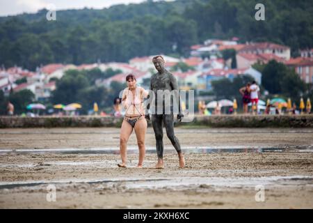 Les gens ont couvert de boue à la plage dans un petit endroit de la Meline, île Krk, Croatie, 14 août,2020. Du début du printemps à la fin de l'automne, la plage du village de Melina est l'une des plus visitées de l'île grâce à la boue curative qui couvre la plage. Les bénéfices de la boue ont été reconnus par beaucoup, en particulier les patients atteints de polyarthrite rhumatoïde qui, après s'être enveloppés de boue, se sentent un grand soulagement.photo: Nel Pavletic/PIXSELL Banque D'Images