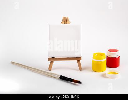 Toile carrée, papier vierge sur chevalet en bois, peinture à la pinceaux et à la gouache en pots. Photo de haute qualité Banque D'Images