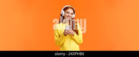 La technologie, le shopping et les gens concept. Hipster mignon moderne redhead girl wearing white casque, holding smartphone, souriant insouciant, profiter d'une belle Banque D'Images
