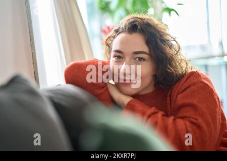 Jeune heureuse jolie femme se reposant sur un canapé à la maison. Portrait Banque D'Images