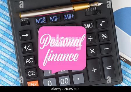 Concept de finance et d'économie. Sur le bureau se trouvent des graphiques, des rapports, une calculatrice et une feuille de notes sur lesquelles il est écrit - Personal Finance Banque D'Images