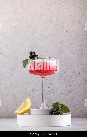 Élégant verre de Black Currant Gin Sour cocktail ou de queues de macktoes entouré d'ingrédients sur la surface de table grise. Boisson rafraîchissante prête à boire. Banque D'Images