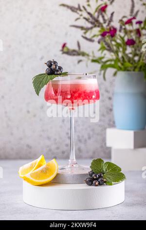 Élégant verre de Black Currant Gin Sour cocktail ou de queues de macktoes entouré d'ingrédients sur la surface de table grise. Boisson rafraîchissante prête à boire. Banque D'Images