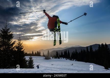 Marmara, les Carpates, UKRAINE - 15 mars 2021: Skieur freestyle extrême saut du kicker dans les montagnes enneigées au coucher du soleil orange, une adrénaline Banque D'Images