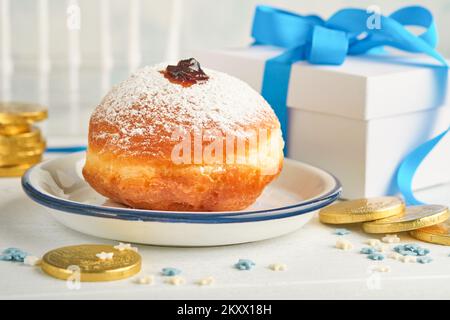 Bonne Hanoukkah. Beignets sucrés Hanukkah, boîtes-cadeaux, bougies blanches et pièces de chocolat sur fond de bois blanc. Image et concept d'holida juif Banque D'Images