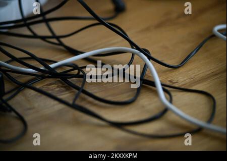 L'encombrement du chaos à partir de plusieurs fils électriques, rallonges et prises multi-contact sur plancher en bois ou d'arrière-plan du tableau Banque D'Images