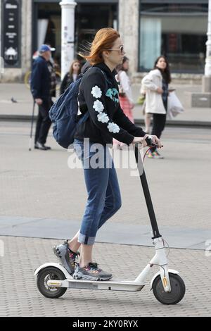 Les gens sont vus en voiture sur des scooters dans le centre-ville. Fin avril, le projet de proposition finale de la loi sur les amendements à la loi sur la sécurité routière a été présenté, qui définit de nouvelles catégories de véhicules, et des modifications ont été apportées concernant l'obligation de porter un casque de protection. Une fois adoptée, la loi introduira de nouvelles catégories: Les scooters, les rouleaux et les patins à roulettes deviennent des aides à la circulation, et les e-scooters et autres véhicules électriques deviennent des moyens de transport personnels. Une autre nouveauté en ce qui concerne le dernier projet de texte juridique est que tous les conducteurs de véhicules personnels wil Banque D'Images