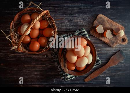 Oeufs de poulet dans une assiette en argile et un panier sur la table Banque D'Images