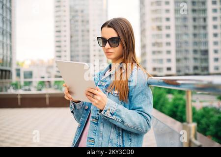 Jeune femme d'affaires Millennials en lunettes marchant Financial District ville utilise la tablette numérique dans les réseaux sociaux, connexion, données, Affichage numérique Banque D'Images