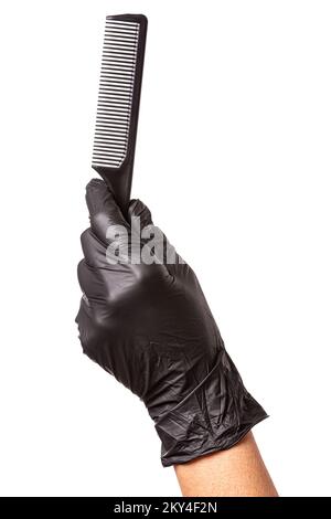 La main de coiffeurs dans le gant en caoutchouc noir tient un peigne.Isolé sur fond blanc, gros plan Banque D'Images