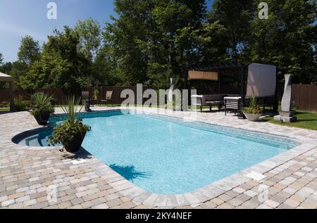 Piscine en plein air et mobilier de jardin dans une cour résidentielle paysagée en été. Banque D'Images