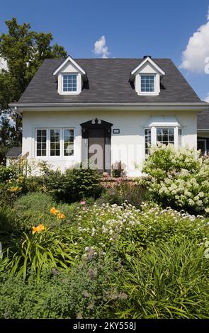 Maison de style manoir Canadiana à deux étages blanc avec bordure noire avec jardin paysagé en été. Banque D'Images