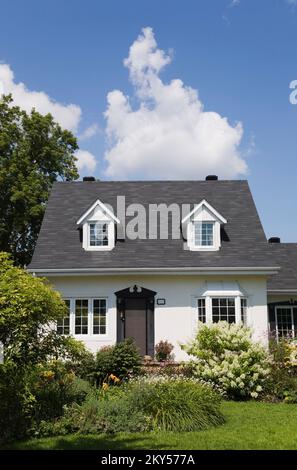 Maison de style manoir Canadiana à deux étages blanc avec bordure noire avec jardin paysagé en été. Banque D'Images