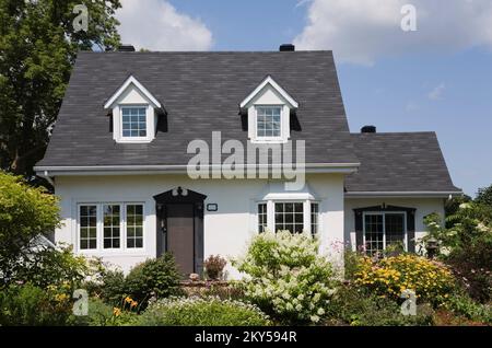 Maison de style manoir Canadiana à deux étages blanc avec bordure noire avec jardin paysagé en été. Banque D'Images