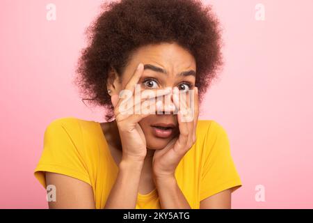 Femme maurique afro-américaine effrayée, étudiante en t-shirt jaune, couvrant son visage avec les mains et la peur Banque D'Images