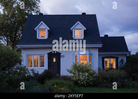 Maison de style Canadiana à deux étages avec cour avant paysagée au crépuscule en été. Banque D'Images