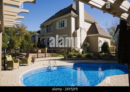 Piscine au sol avec meubles de jardin dans une cour paysagée entourée de pergola en été. Banque D'Images