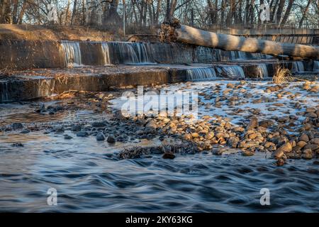 Eau en cascade au-dessus d'un barrage de dérivation sur la rivière poudre avec décor d'automne ou d'hiver, concept de nature et d'industrie Banque D'Images
