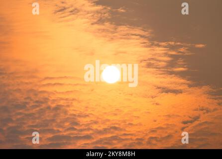 Le soleil se lève au-dessus de quelques nuages lors d'un matin d'été brumeux Banque D'Images