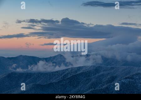 Coucher de soleil spectaculaire sur les montagnes d'hiver couvertes de forêt d'épicéa enneigé, hiver dans les Carpates. Papier peint d'hiver idyllique. Banque D'Images