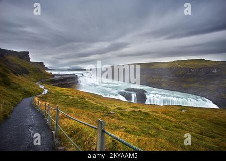 Un lever de soleil nuageux jette une lueur mystique sur la cascade de Gullfoss, où la cascade rugissante rencontre les teintes sereines du ciel islandais Banque D'Images