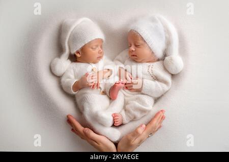 Nouveau-né deux garçons en bodys blancs sur fond blanc. Banque D'Images