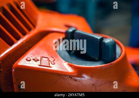Réservoir de remplissage du mélange de carburant avec de l'huile dans la tronçonneuse. Symbole de station d'essence et de lubrifiant sur le corps d'une tronçonneuse orange. Huile de graissage a Banque D'Images