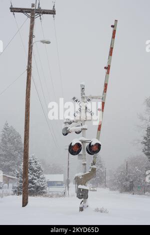 Passage à niveau en 3 sens, panneau et feux d'avertissement au passage à niveau du chemin de fer 3rd Street, par une journée enneigée, à Troy, Montana. Burlington Nord et Sant Banque D'Images