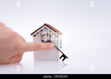 Main tenant une clé d'or près d'une maison sur un fond blanc Banque D'Images