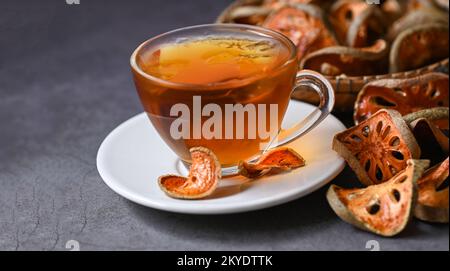 Thé Bael sur verre avec tranches de bael séchées sur fond de bois, jus de Bael - thé sec aux fruits de bael pour la santé - Aegle marmelos Banque D'Images