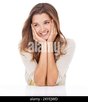 Penser à vous. Photo studio d'une jeune femme heureuse assise avec sa tête reposant dans les mains et regardant réfléchie. Banque D'Images