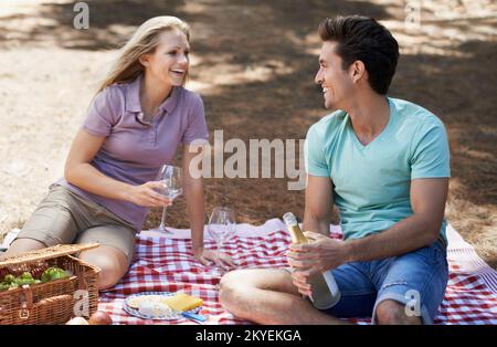 C'est parfait. Vue sur un jeune couple heureux ayant un pique-nique d'été et appréciant une boisson de fête. Banque D'Images