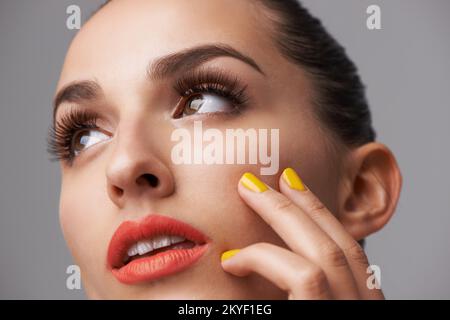 Beauté définie par la couleur. Une jeune femme attirante portant un rouge à lèvres et un vernis à ongles coloré. Banque D'Images
