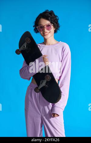 Portrait d'une jeune fille heureuse tenant un skateboard Banque D'Images