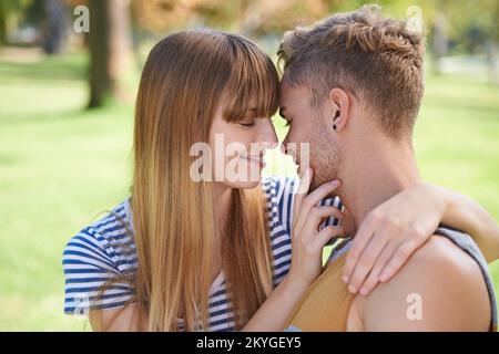 Personne d'autre dans le monde... un jeune couple qui partage un moment tendre ensemble tout en appréciant une journée dans le parc. Banque D'Images