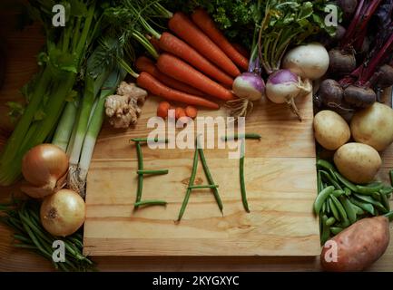 Frais de la terre. Photo de la vie d'une variété de légumes sur une planche à découper avec le message manger. Banque D'Images