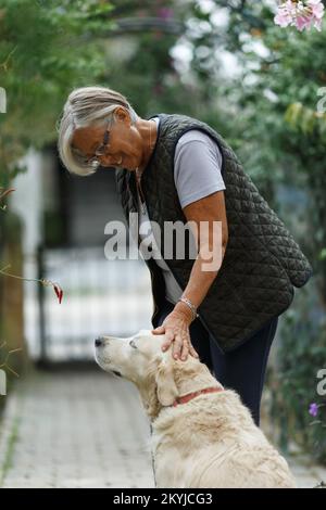 Femme âgée avec chien dans la nature printanière, au repos Banque D'Images