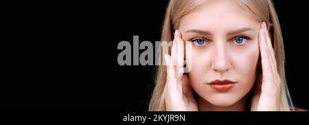 Maux de tête, migraine. Prise de vue d'une jeune femme touchant ses temples se transformant en appareil photo sur une bannière noire. La femme blonde aux yeux bleus regarde droit devant Banque D'Images