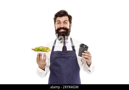 Concept Cafe Food. Homme barbu serveur porter tablier porte plaque avec nourriture et tasse de café. Profitez de votre repas. Un gars qui sert des croissants, de la laitue farcie et Banque D'Images