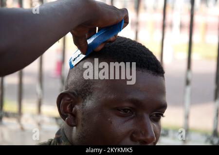 Un soldat obtient une coupe de cheveux, Kinshasa, République démocratique du Congo, avec un peigne et un rasoir. Banque D'Images