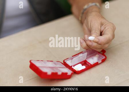 Les mains de la femme senior prennent des pilules de la boîte. Santé et vieux concept avec des médicaments. Médicaments sur la table Banque D'Images